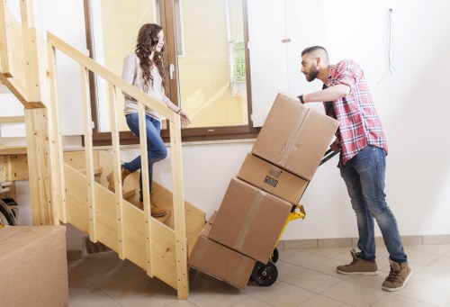 Movers handling furniture in a Highbury flat with stairs
