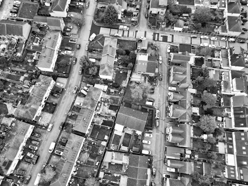 An aerial black-and-white photograph showing a narrow residential street in Highbury, with a row of parked cars lining both sides of the road. Behind the parked vehicles, there are closely packed terr
